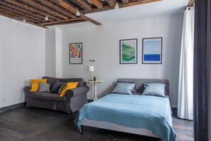 Un dormitorio moderno con una cama, un sofá y dos obras de arte enmarcadas en la pared.