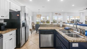 A modern kitchen with white cabinetry, granite countertops, stainless steel appliances, and a built-in dishwasher. - Private Heated Pool Hot Tub Gulf View Elevator (Gulf Shores)