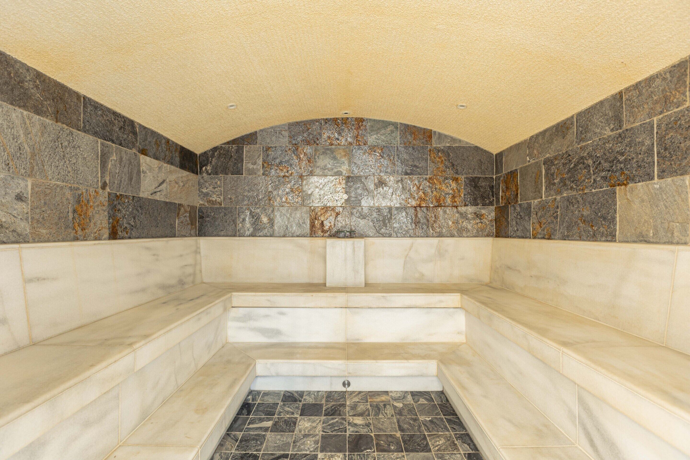 A spa area with a stone wall, marble steps, and a tiled floor.