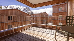 Una terraza de madera con una mesa y sillas, con vistas a una montaña nevada.