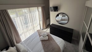 A hotel room with a bed, a TV mounted on the wall, and a large window with curtains. - Malton 2-bed Lodge, Sleeps 4, Pet Friendly (Malton)
