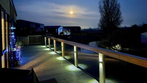 A wooden deck with railings, a view of a house, and a body of water. - Malton 2-bed Lodge, Sleeps 4, Pet Friendly (Malton)