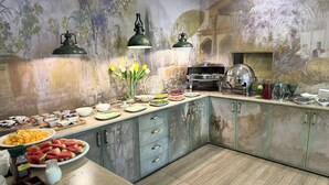 A kitchen with a rustic design, featuring a long counter with various food items and a grill. - NMetechi  (Tbilisi)
