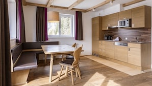 A modern kitchen with wooden cabinets, a built-in microwave, and a dining area with a bench and table. - Superior Chalet With Finnish Sauna (Hermagor-Pressegger See)