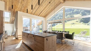 Eine moderne Küche mit einer Holztheke, großen Fenstern und Blick auf eine grüne Landschaft.