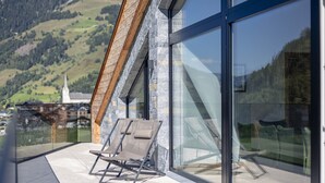 Ein Balkon mit Glasbrüstung und Blick auf eine Berglandschaft.