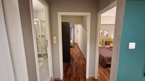 A hallway with a shower, a bed with pillows, and a door leading to another room. - AIOLOU st - 7th floor - 2 bdr, 80m2, most central apt - NetFlix - sleep 4p (Athina)