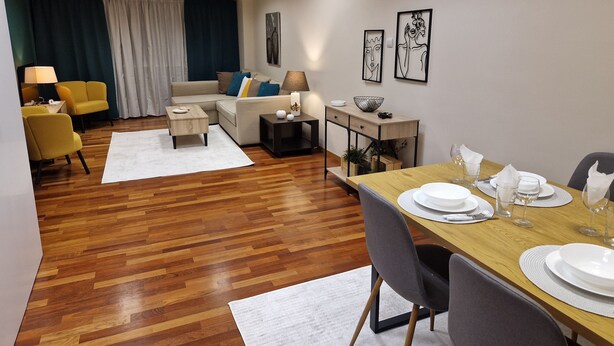 A modern living room with a sofa, chairs, a dining table set for four, and artwork on the walls. - AIOLOU st - 7th floor - 2 bdr, 80m2, most central apt - NetFlix - sleep 4p (Athina)