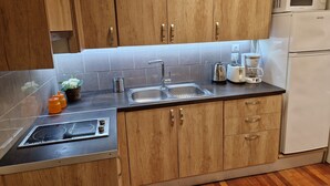 A kitchen with wooden cabinets, a stainless steel sink, a microwave, a coffee maker, and a toaster. - AIOLOU st - 7th floor - 2 bdr, 80m2, most central apt - NetFlix - sleep 4p (Athina)