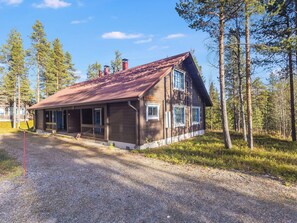 A wooden cabin with a porch, surrounded by trees.