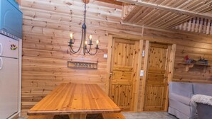 Een houten interieur met een houten tafel, bankjes, een bank en een plafondlamp.
