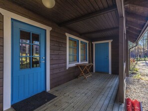 A wooden building with blue doors and windows, a covered porch, and a small table.