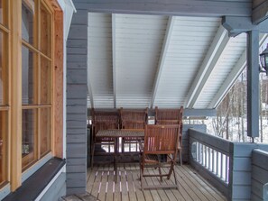 A covered porch with wooden furniture and a view of trees. - Talvilaakso by Interhome (Nilsiä)