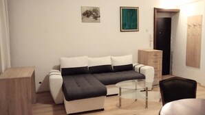 A modern living room with a sofa, a glass coffee table, a wooden side table, and a chair. - Comfortable apartment in delightful Beograd with WiFi, AC (Beograd)
