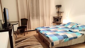 A hotel room with a bed, a desk, a chair, a cat tree, and a window with curtains. - Comfortable apartment in delightful Beograd with WiFi, AC (Beograd)