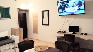 A modern living room with a TV, a dining table, and a sofa. - Comfortable apartment in delightful Beograd with WiFi, AC (Beograd)