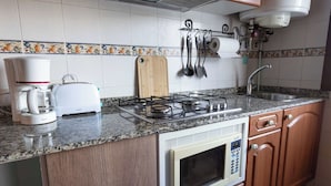 Una cocina con estufa a gas, cafetera, tostadora, microondas y armarios de madera.