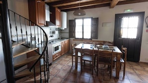 Una cocina con armarios de madera, una mesa de comedor y una escalera.