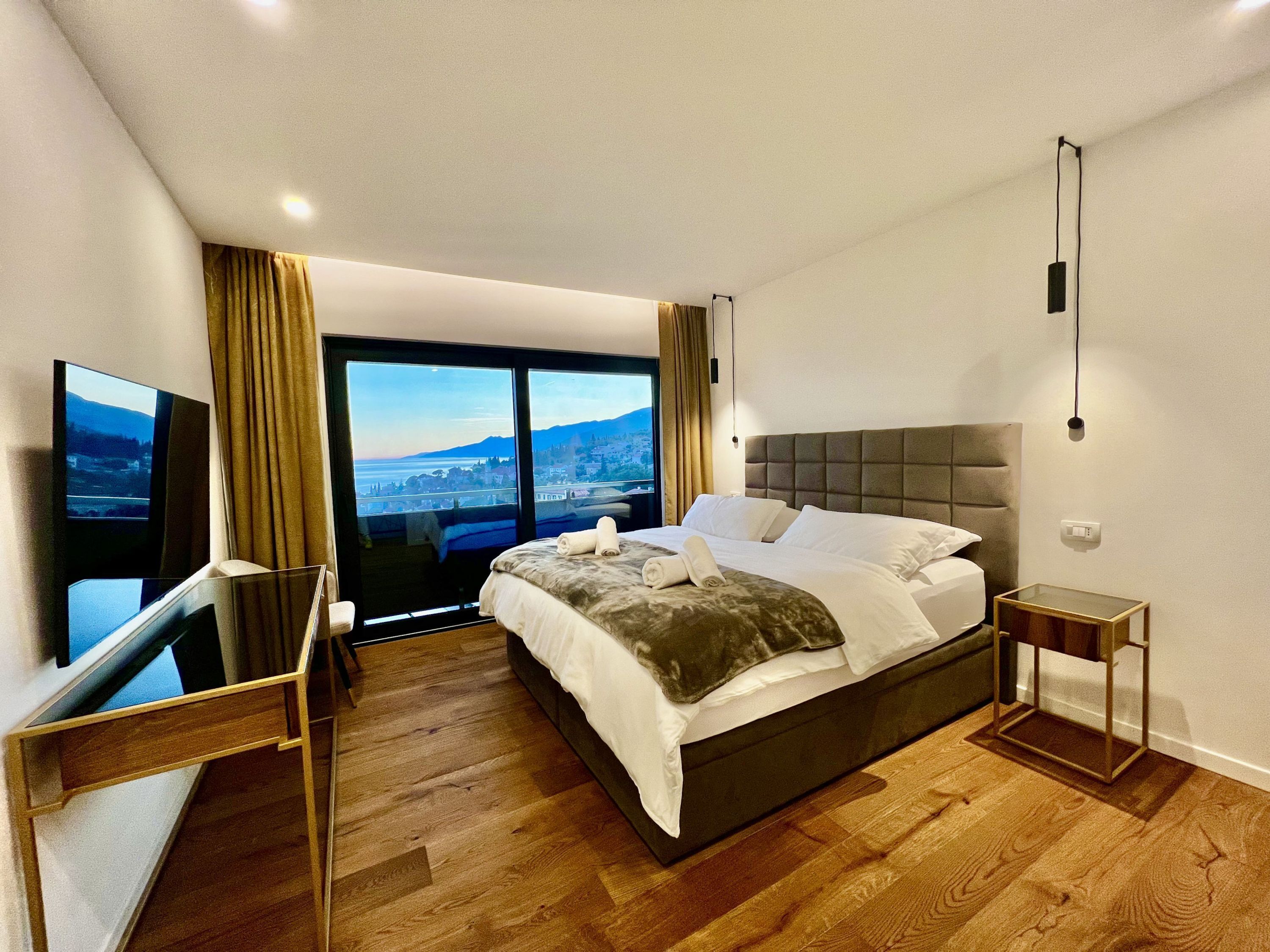 A modern hotel room with a large bed, a TV, and a city view.