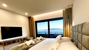Habitació d'hotel amb un llit gran, una televisió de pantalla plana i vista a l'oceà.