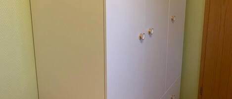 A bedroom with a large wardrobe, a bed with floral bedding, and a carpeted floor.
