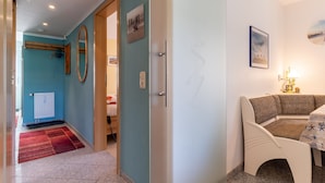 A room with teal walls, a white door, a wooden bench, and a table with a lamp. - Ferienwohnung fur 3 in St. Peter-ording (St. Peter-Ording)