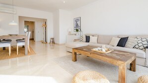 Ein modernes Wohnzimmer mit einem Holztisch, einem weißen Sofa und einem Essbereich mit Tisch und Stühlen.