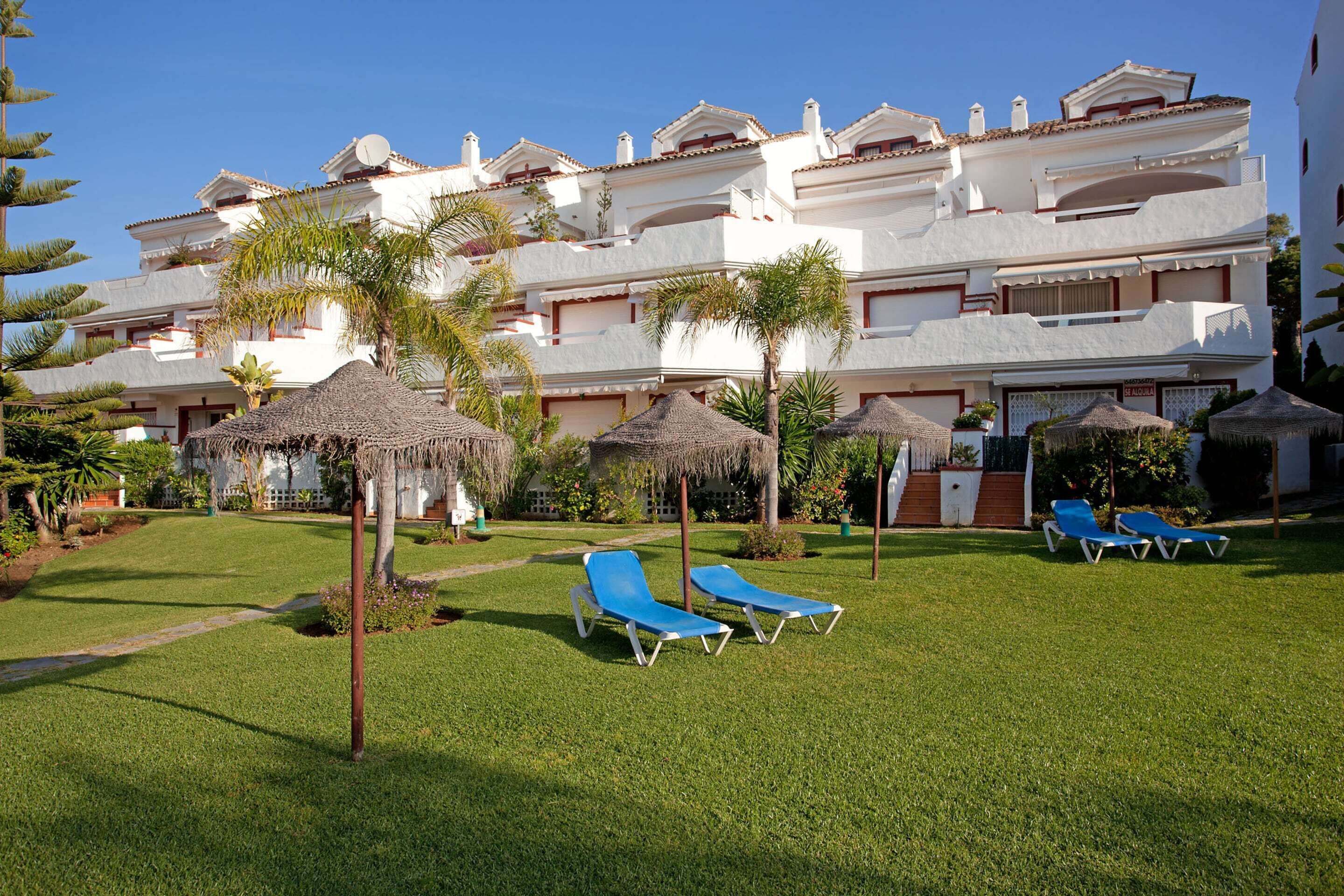 A hotel with multiple balconies, a well-maintained lawn, and several lounge chairs.