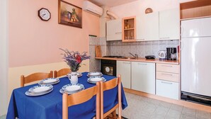 Una cocina con una mesa de comedor para dos personas, una estufa, un refrigerador y un reloj en la pared.