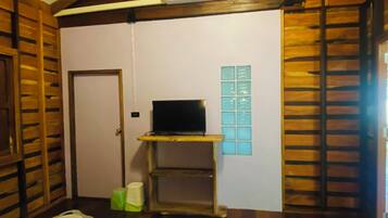 A room with a wooden door, a television on a wooden stand, and a wall with a blue tile pattern.
