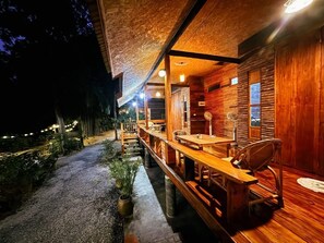 Une cabane en bois dotée d’une terrasse couverte, de sièges d’extérieur et d’une petite table.