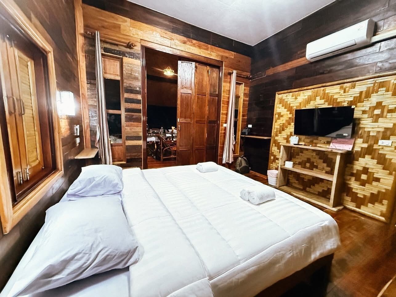Une chambre à coucher avec un lit, une armoire en bois et un téléviseur posé sur une étagère en bois.