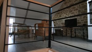 Un intérieur moderne avec un mur en pierre, un fauteuil en osier et un téléviseur à écran plat.