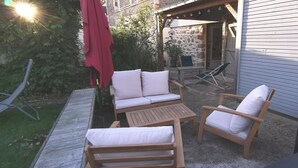 Une terrasse dotée de mobilier en bois, comprenant un canapé et des fauteuils, ainsi qu’une table.