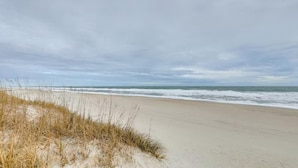 Una playa con dunas de arena y olas del océano.
