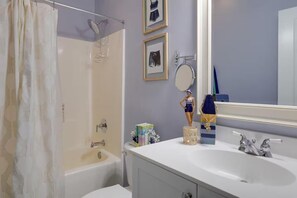 A bathroom with a bathtub, a sink, a mirror, and a shower curtain.
