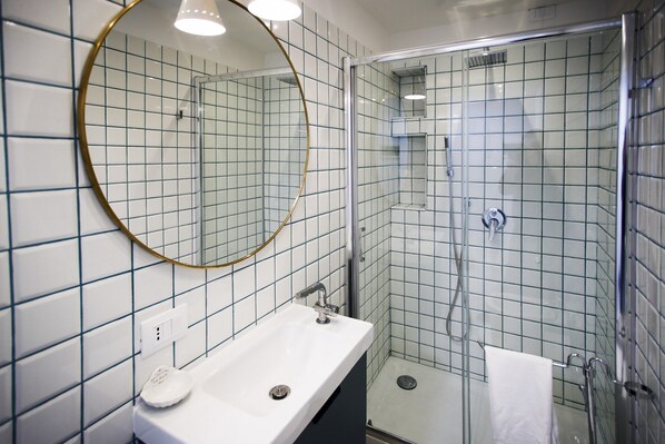 A bathroom with a white sink, a round mirror, and a glass-enclosed shower.