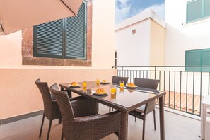 A balcony with a table and chairs, a window with shutters, and a building in the background. - Cassia Loft by Atlantic Holiday (Funchal)