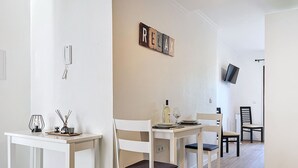 Ruokailutila, jossa on valkoinen pöytä, johon on katettu neljälle, seinälle asennettu televisio ja kyltti, jossa lukee ”RELAX”.