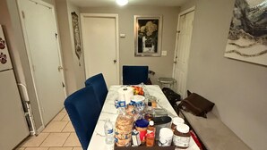 A dining area with a table set for four, featuring a variety of food items and beverages.