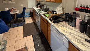 A kitchen with wooden cabinets, a microwave, a stove, and a dishwasher. There is a dining area with a table and chairs.