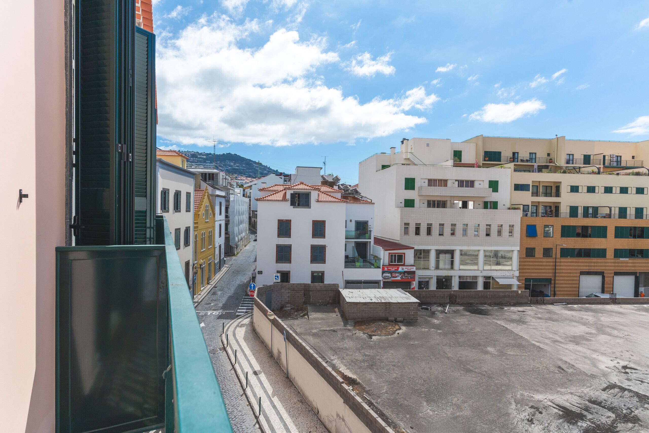 A street view with buildings, a clear sky, and a distant mountain.