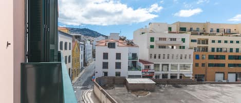 A street view with buildings, a clear sky, and a distant mountain.