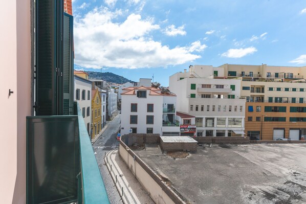 A street view with buildings, a clear sky, and a distant mountain.