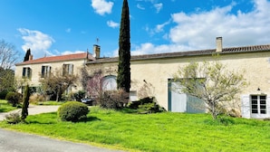 A traditional stone building with a red-tiled roof, a tall cypress tree, and a well-maintained lawn. - Beautiful gite set among vineyards with hot tub and use of heated swimming pool (Loubens)
