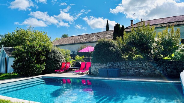 A swimming pool with lounge chairs and a stone wall. - Beautiful gite set among vineyards with hot tub and use of heated swimming pool (Loubens)
