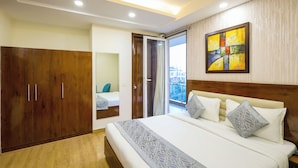 A bedroom with a large bed, a wardrobe, and a sliding glass door leading to a balcony. - Nikko Palm Near Huda City Centre (Gurugram)