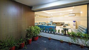 A modern hotel lobby with a seating area, potted plants, and a reception desk. - Nikko Palm Near Huda City Centre (Gurugram)