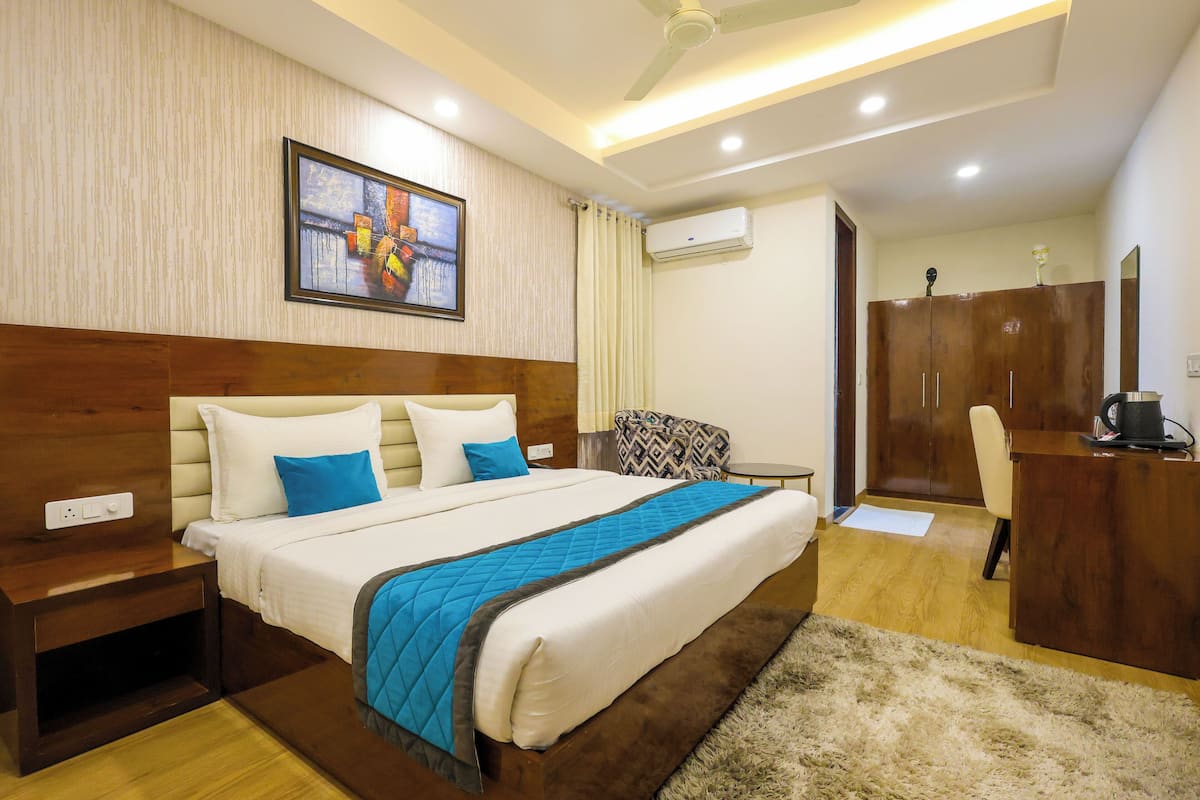 A hotel room with a large bed, a desk, a wardrobe, and a ceiling fan.