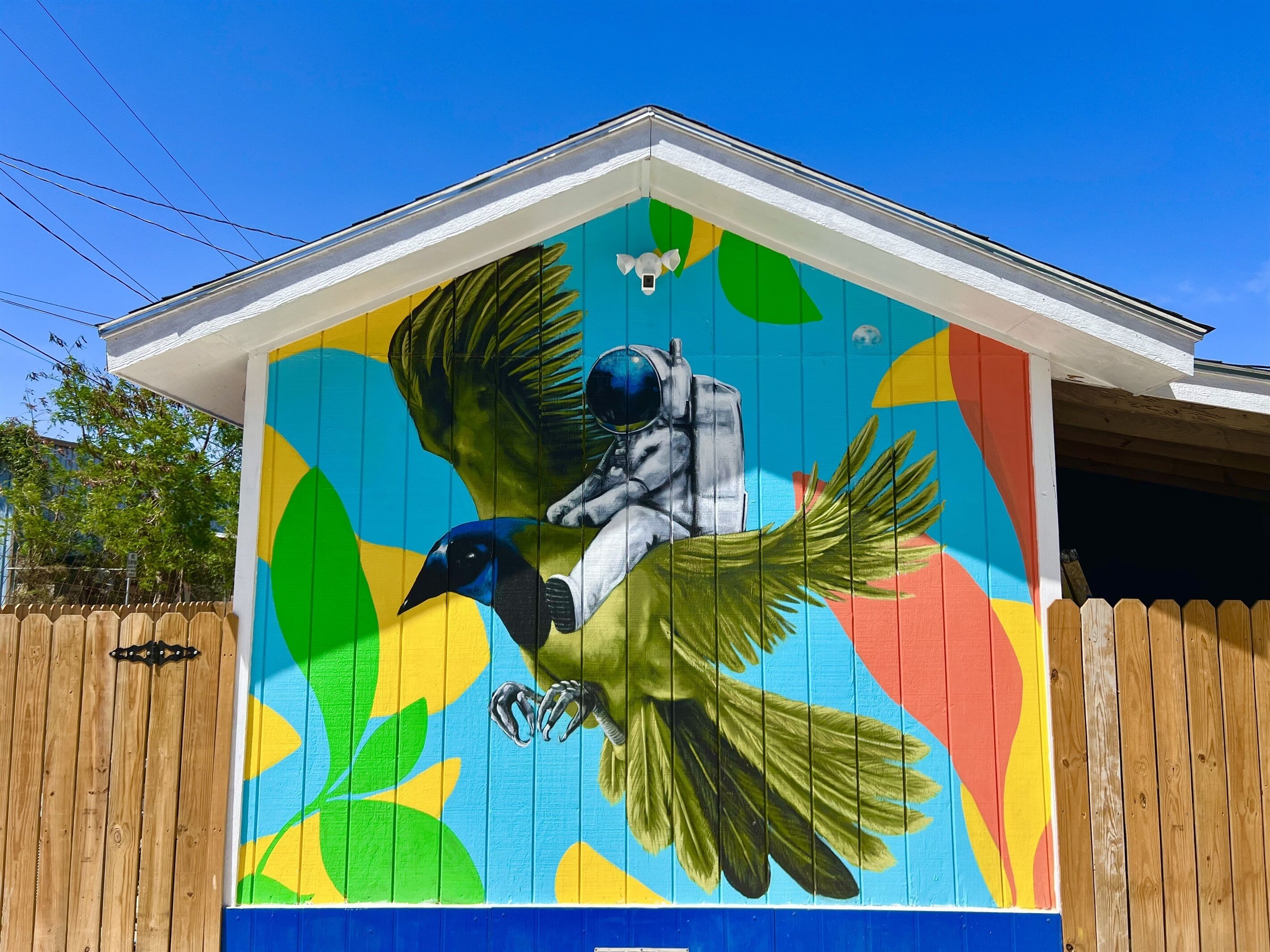 A colorful mural of a bird and astronaut on a building.